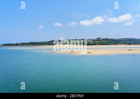 White sand beach with small boats and blue sky in summer. San Vicente de la Barquera. Stock Photo