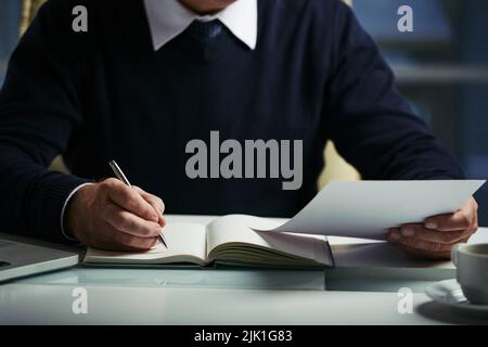 Cropped image of businessman reading documents and taking notes Stock Photo