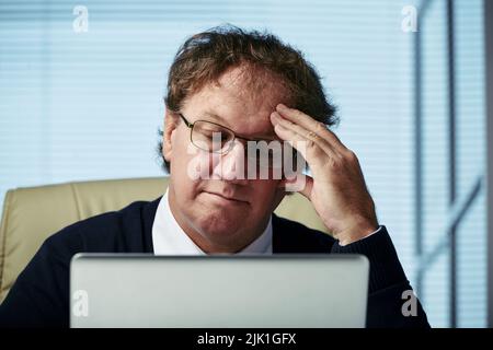 Face of businessman tired of reading reports on laptop Stock Photo