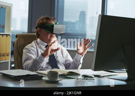 Businessman in VR goggles working at his table in office Stock Photo