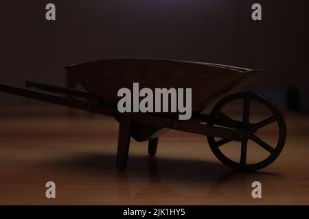 The silhouette of an old wheelbarrow carrying certain bulky things photographed on a brown surface Stock Photo