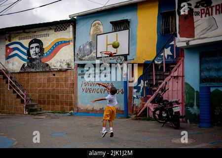 Caracas, Venezuela. 28th July, 2022. A child plays basketball in the 23 de Enero neighborhood surrounded by murals depicting Ernesto Che Guevara, the late President Hugo Chavez and mottos such as 'We will live and win.' Credit: Pedro Rances Mattey/dpa/Alamy Live News Stock Photo