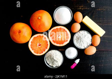 Pink Grapefruit Dessert Bar Ingredients on a Wood Table: Red grapefruit, flour, sugar, an other ingredients on a dark background Stock Photo