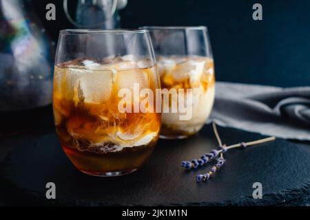 Honey Lavender Cold Brew Latte: Iced coffee with lavender syrup and almond milk over ice cubes Stock Photo