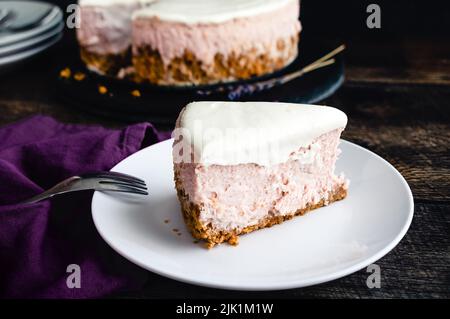 Slice of Honey Lavender Cheesecake Overhead View: Slice of pastel colored cheesecake on a plate with a fork Stock Photo