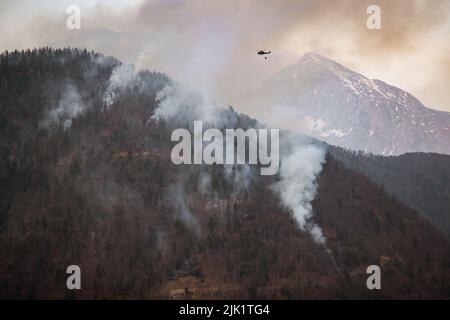 Wildfire firefighting in forest with helicopter carrying a water bucket Stock Photo
