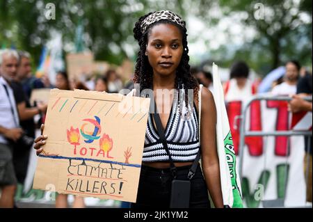 Turin, Italy. 29 July 2022. Climate activist Patience Nabukalu holds a placard reading 'Total climate killers' during a demonstration against government action towards climate breakdown and environmental pollution. The demonstration was organized by Fridays For Future movement and followed five days of Climate Social Camp an international event which brought together activists from around the world. Credit: Nicolò Campo/Alamy Live News Stock Photo