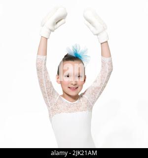 Smiling girl ballet dancer 9-year-old in white ballet tutu skirt and arms raised in mittens. Studio shot ballerina on white background. Part of photo Stock Photo
