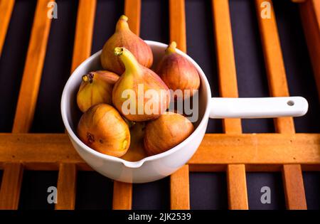 Fresh organic figs in white pot on the wood background Stock Photo