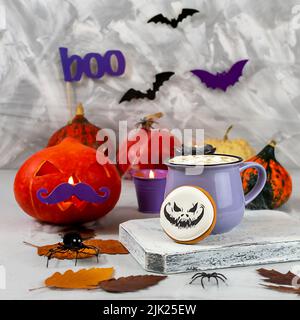 Halloween pumpkin and mug of coffee with cookies on the background of a gray wall with ghosts, bats, spiders, candles, pumpkins. leaves. Selective Stock Photo