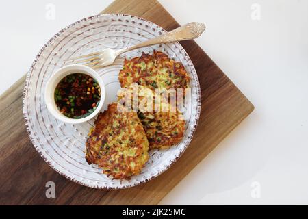 Zucchini fritters, vegetarian zucchini fritters on a white plate served with soy sauce in a small white bowl. Vegetarian food Stock Photo