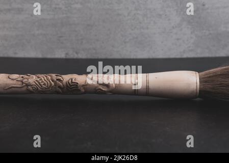 Chinese hand carved bone paintbrush on grey and black background. Stock Photo