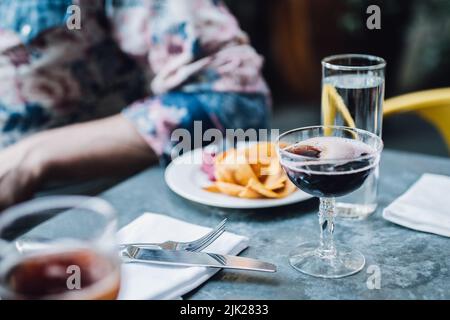 dining outdoors at restaurant with glass of red wine and plate of plantain chips and dips Stock Photo