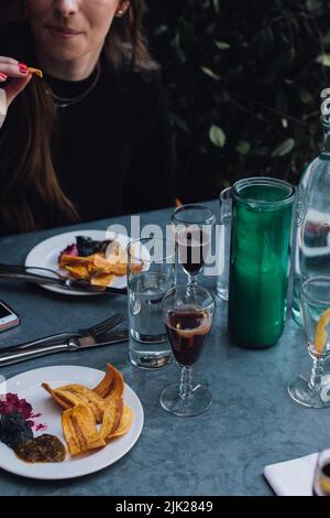 woman eating Plantain chips and dips at outdoor restaurant on metal patio table with wine glasses Stock Photo