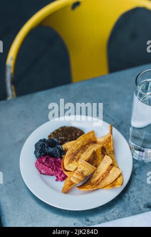 plantain chips and dips at outdoor restaurant with yellow metal cafe chair Stock Photo