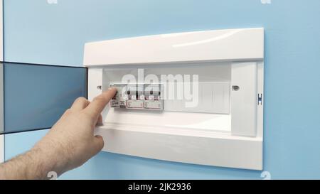 Circuit breaker board displays many switches. A finger is about to turn it back on. Stock Photo