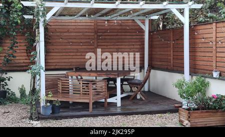 Gazebo with lights at night. Picture of a summer house with comfortable garden furniture. Romantic scene in dusk Stock Photo