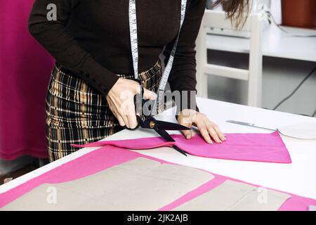 Female fashion designer tailor making sewing patterns at workplace in sewing studio. Seamstress working Stock Photo