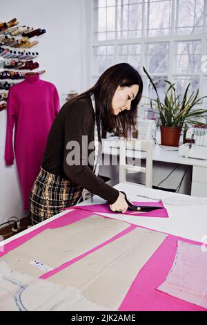 Female fashion designer tailor making sewing patterns at workplace in sewing studio. Seamstress working Stock Photo