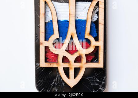The wooden coat of arms of Ukraine lies on the painted flag of Russia on a white background, Ukraine and Russia, war Stock Photo