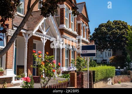 Estate agent SOLD sign with defocussed street of houses in background Stock Photo