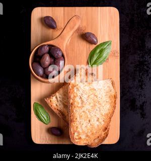 Olives and rustic homemade bread on wood table Stock Photo