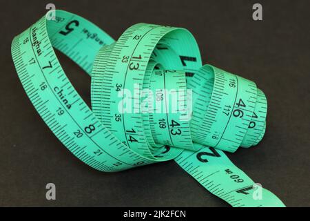 Green tailor's tape measure in centimeters and inches Stock Photo