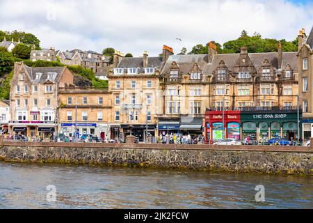 Oban town centre waterfront on sunny summers day, high street shops and tourists in the town overlooked by McCaig's tower,Oban,Argyll,Scotland,UK Stock Photo