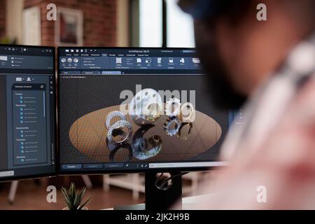 Developer prototyping machinery product on computer, wearing headphones and creating industrial gears model on technical software. Developing machine engine graphics and 3d manufacture. Stock Photo