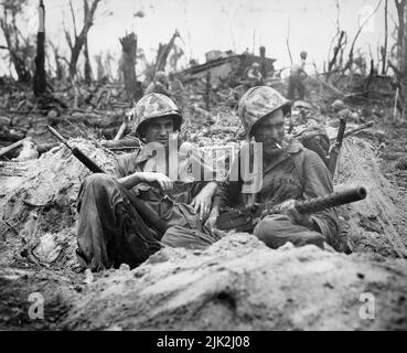 Marine Private First Class Douglas Lightheart (right) cradles a 30-caliber machine gun in his lap, while he and his buddy Private First Class Gerald Churchby take time out for a cigarette, while mopping up the enemy on Peleliu Islands Stock Photo