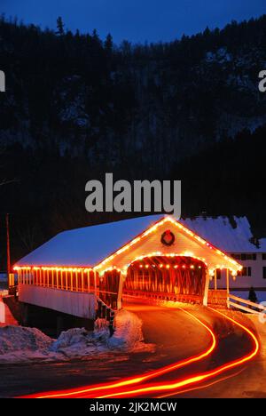 A covered bridge is decorated and illuminated with Christmas lights for the holiday in a small charming village in New England Stock Photo