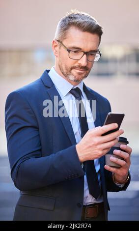 Checking his messages. a handsome mature businessman texting while standing outside in the city. Stock Photo