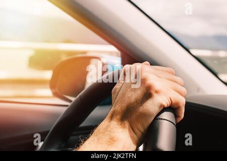 Man's hand on the steering wheel close-up, man driving a car Stock Photo