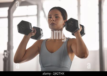 Fit, active and strong athlete doing arm muscle training and exercises with dumbbells or weights at a gym for a wellness lifestyle. Closeup of sporty Stock Photo