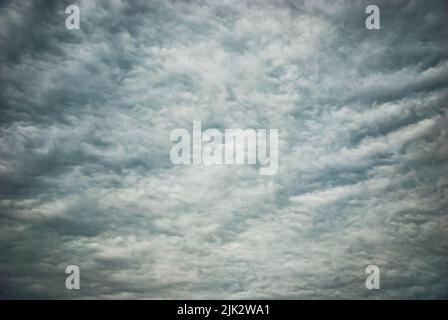 Moody overcast sky background, fleecy clouds texture, ominous skies in cold windy weather Stock Photo