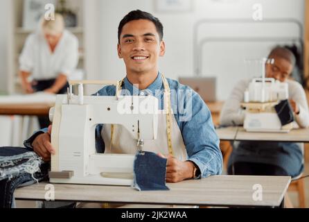 Young adult fashion designer in sewing workshop. Professional man in clothing and material design at work with diverse group of employees. Creative Stock Photo