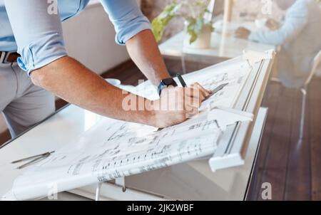 Architect drawing a plan for a building project inside his office. Closeup of a male engineer doing a blueprint sketch at an architecture company or Stock Photo