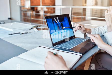 Architect, design engineer or contractor pointing to a 3d digital model on a laptop screen, discussing a plan or idea with a colleague in a meeting Stock Photo