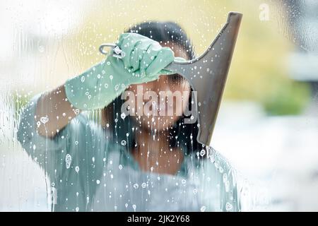 Make sure your squeegee is clean. a young woman cleaning her windows. Stock Photo