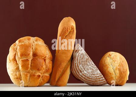 Various Rustic Bread, Sourdough, Baguette, Boule Isolated on Brown Table. Copy Space for Text or Recipe Stock Photo