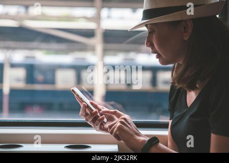 Beautiful young woman traveler using smartphone at a train station , Transportation and travel lifestyle concept Stock Photo