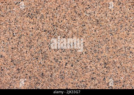 Real stone granite wall in brown color with polished surface. Textured stone background in brown with black splashes. Stock Photo