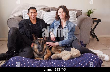 Weve got a mixed family. a young couple sitting in their living room with their German Shepherd during a day at home.