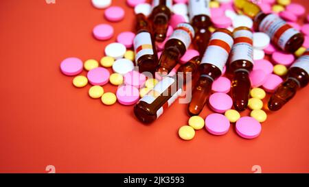 Multi-colored pills and ampoules on a pink background. Tablets and ampoules without packaging on a pink surface Stock Photo