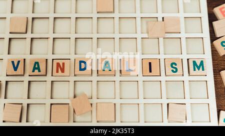 Vandalism - problem in society. Small wooden square letters put together on a white board and creating a word. High quality photo Stock Photo