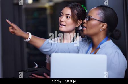 We should check that one next. two attractive young female computer programmers working together in a server room. Stock Photo