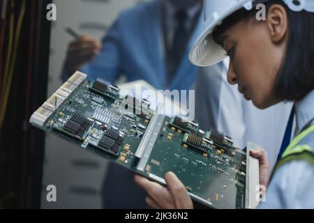 Marvelling at miracles. a young woman closely inspecting a motherboard in a server room. Stock Photo