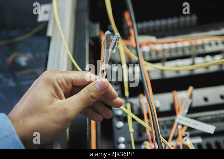 Same skills as a surgeon, different scalpels. an unrecognizable woman working on cables in a server room. Stock Photo
