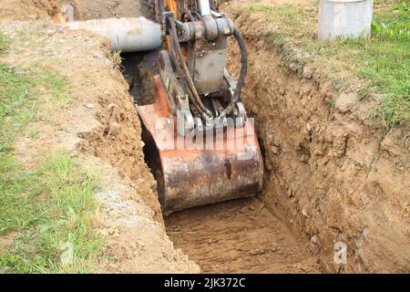 Excavator shovel digs into loamy soil Stock Photo