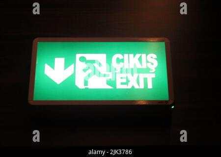 Green light signboard (The Turkish meaning of exit is çıkış). Close-up photo of emergency exit sign. Isolated on black background. No people, nobody. Stock Photo